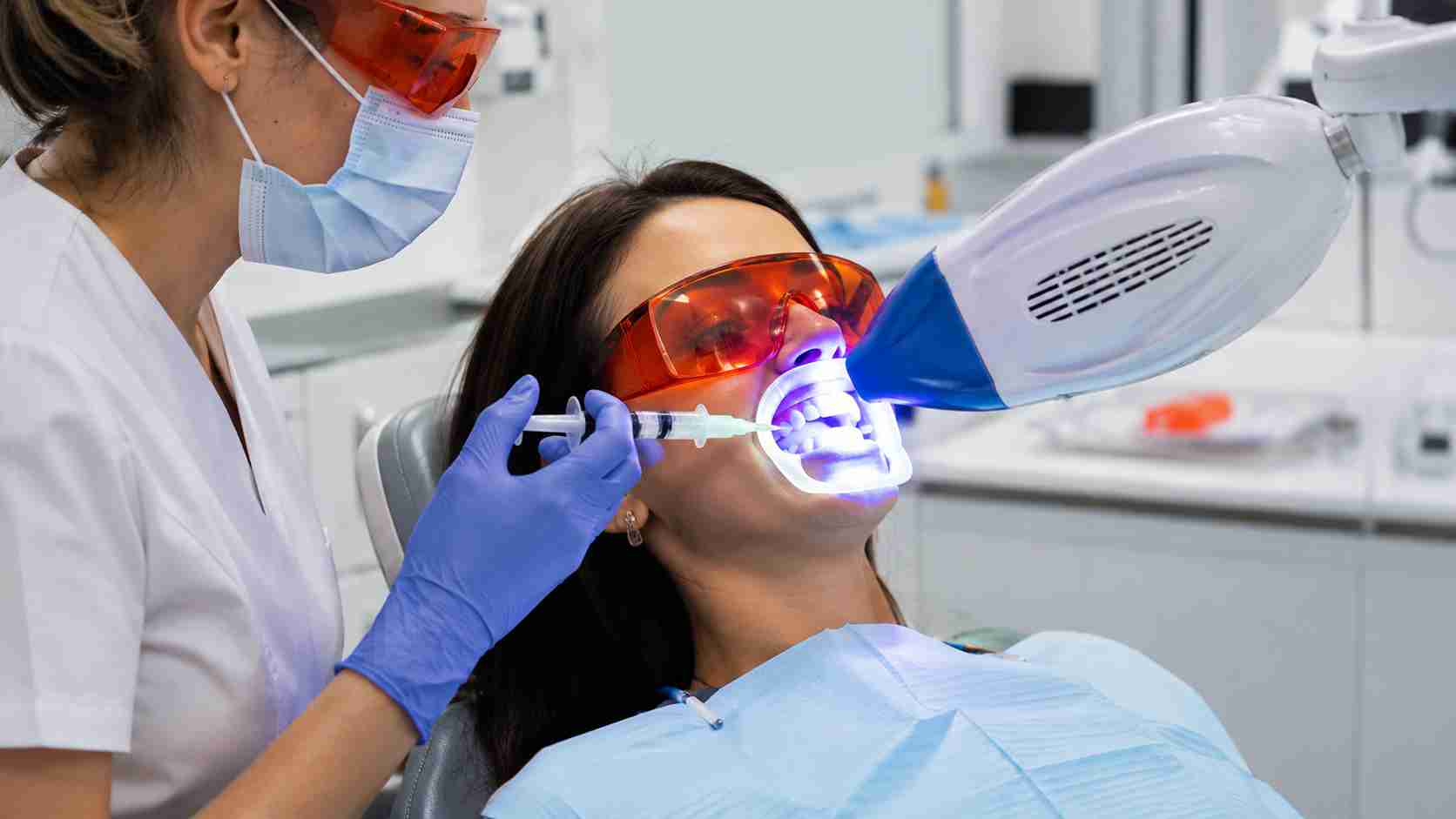 Dentist performing Zoom teeth whitening procedure using LED whitening light