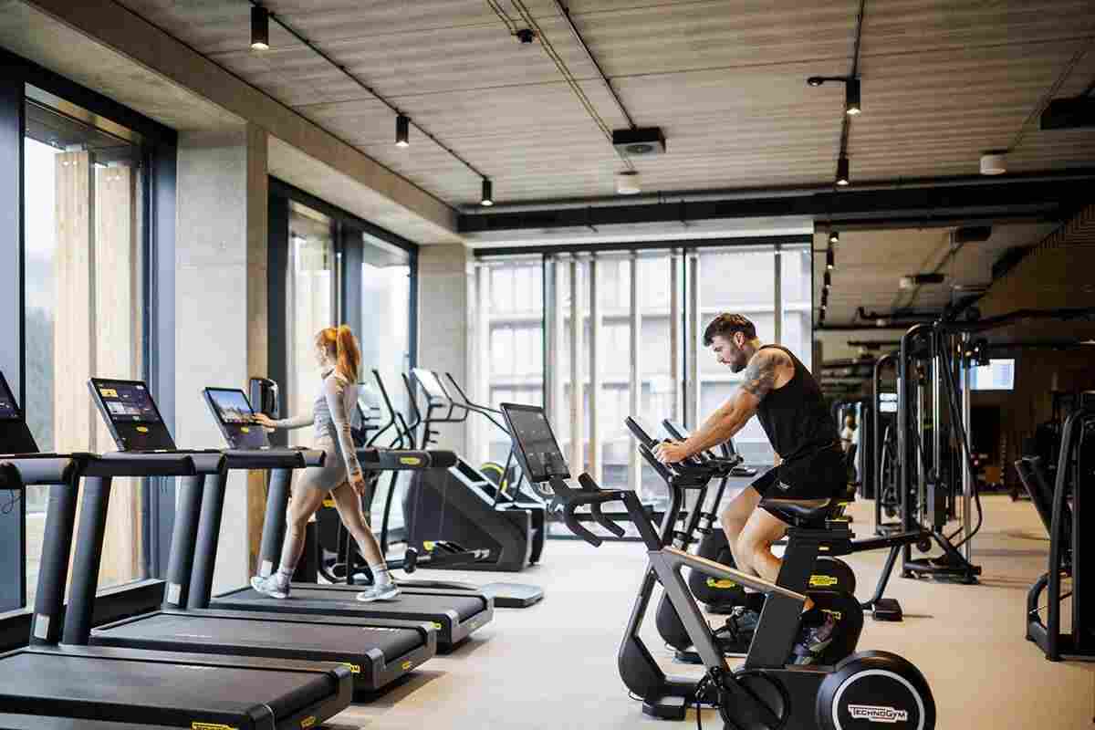 Stationary exercise bike compared with treadmill inside a modern fitness gym.